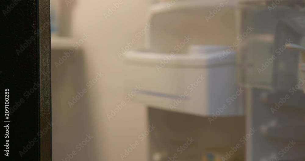 Pan across to CU on woman's hand as she opens and closes stainless steel fridge door, revealing out of focus interior with water dispenser. Real-time 4K Pan across to CU on woman's hand as she opens and closes stainless steel fridge door, revealing out of focus interior with water dispenser. Real-time 4K