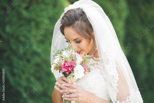 Beautiful luxury young bride in wedding dress posing in park