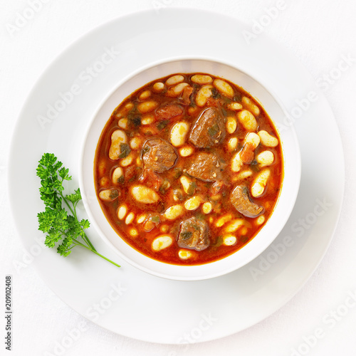 white beans and meat casserole cooked in tomato red wine gravy and decorated with parsley