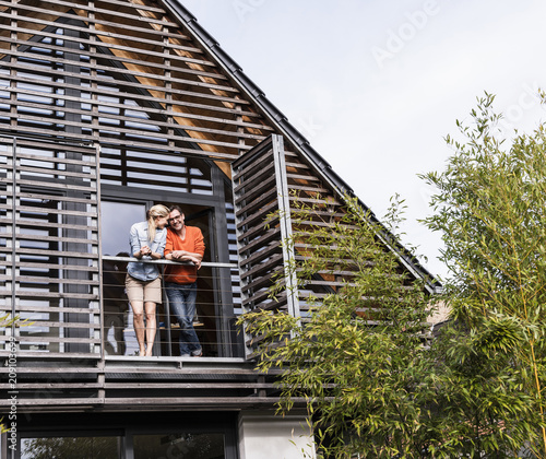 Happy mature couple standing on balcony of their house