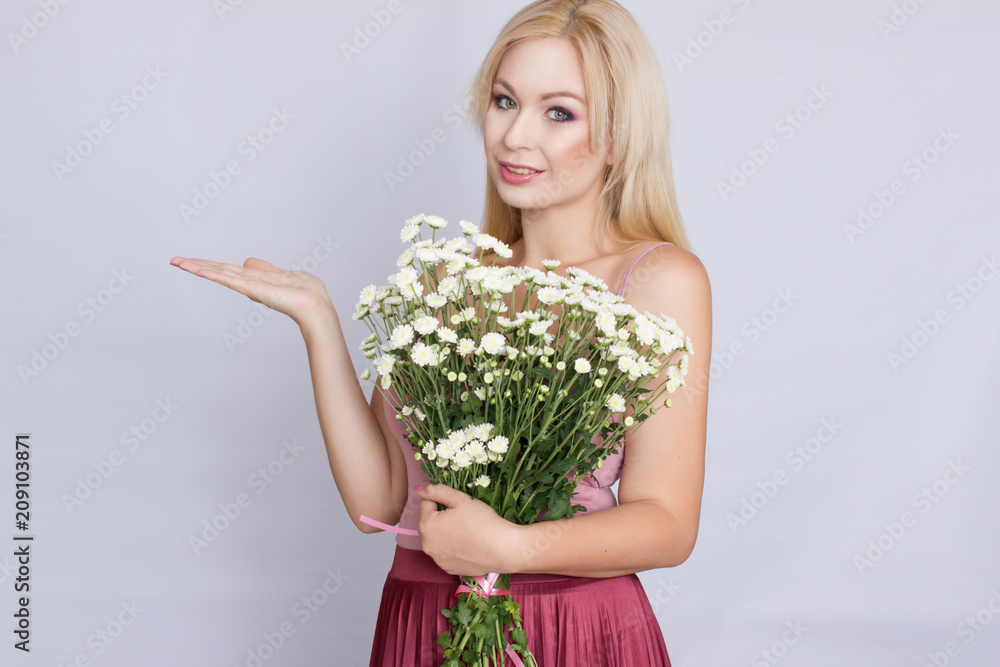 Portrait of a happy blonde woman in pink attire holding a bouquet of white wildflowers in hands Portrait of a happy blonde woman in pink attire holding a bouquet of white wildflowers in hands