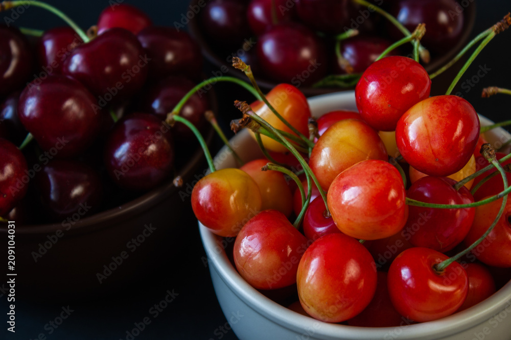 Ripe juicy cherries on a black background. Delicious cherries in plates. Ripe juicy cherries on a black background. Delicious cherries in plates.