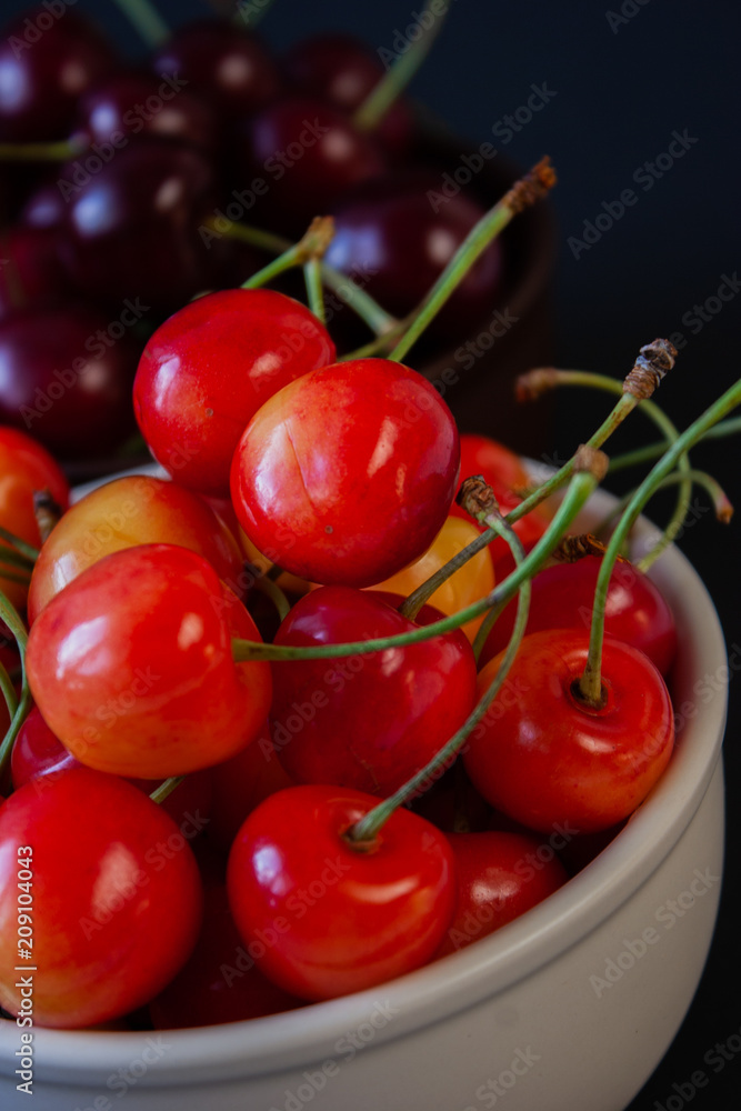 Ripe juicy cherries on a black background. Delicious cherries in plates. Ripe juicy cherries on a black background. Delicious cherries in plates.