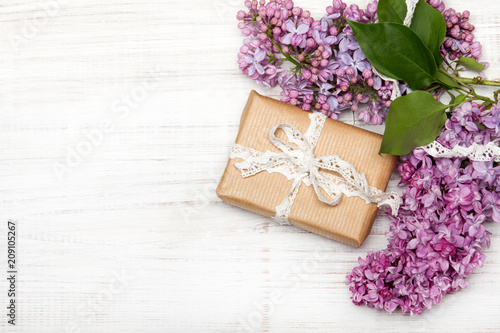 Fototapeta Naklejka Na Ścianę i Meble -  Lilac flowers, gift box on white wooden background, copy space