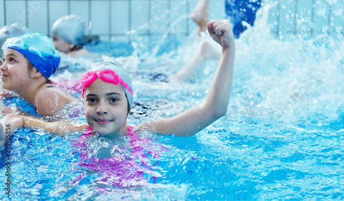 Happy children kids group at swimming pool class learning to swim