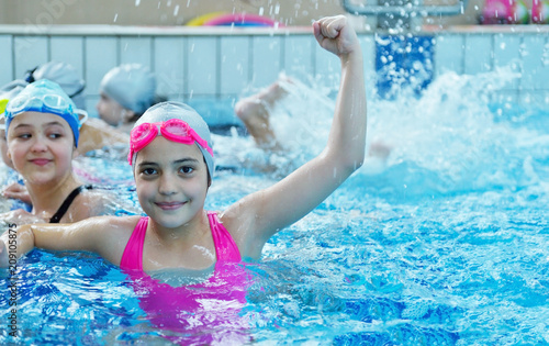 Happy children kids group at swimming pool class learning to swim
