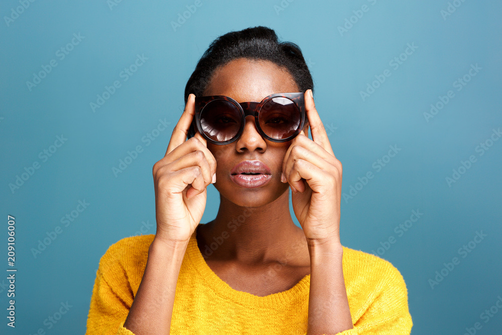 trendy young black woman in sunglasses by blue wall trendy young black woman in sunglasses by blue wall