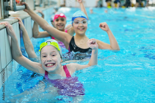 Happy children kids group at swimming pool class learning to swim