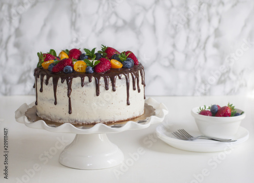 Homemade chocolate birthday cake with berry jelly, ceam cheese, chocolate decorations and berries photo