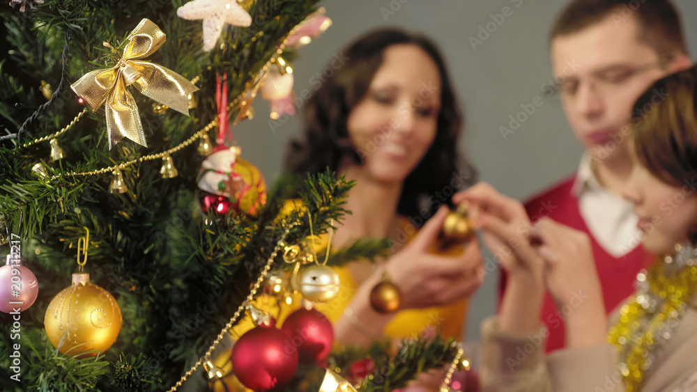 Loving parents helping their daughter to decorate Christmas tree, magic moments