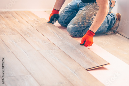 Professional installation of floor covering, the worker quickly and qualitatively mounts a laminate board