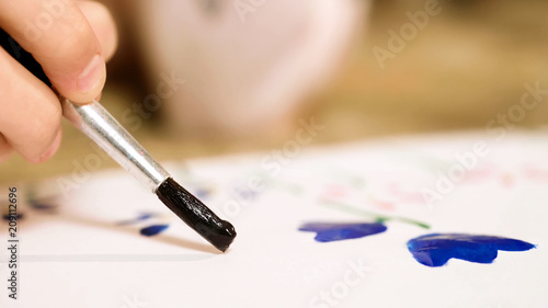 Closeup of child hand carefully drawing flowers with gouache  creativity  talent