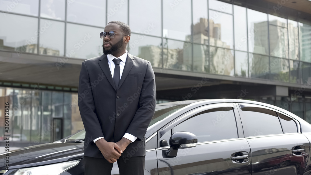 Huge Afro-American security chief monitoring order outside business center Huge Afro-American security chief monitoring order outside business center