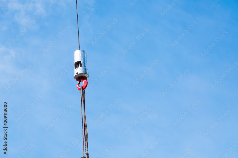 The hook of elevating crane lifts a concrete plate against the blue sky, close up The hook of elevating crane lifts a concrete plate against the blue sky, close up