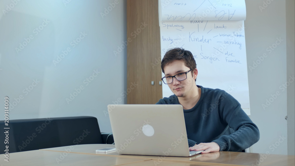 Young man video conferencing with tutor on laptop in class room Young man video conferencing with tutor on laptop in class room
