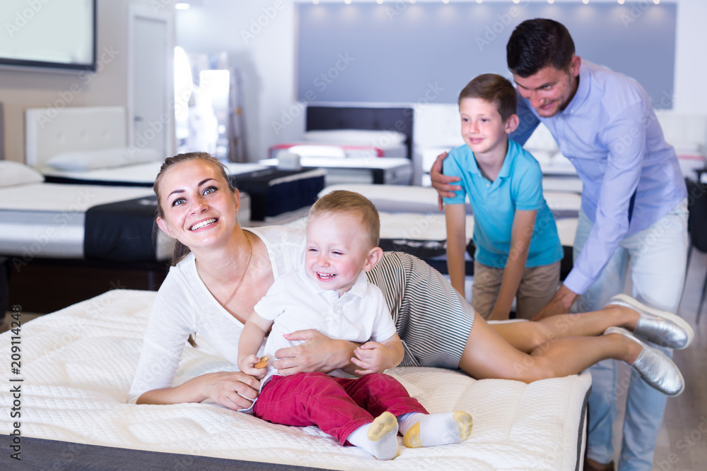 Young woman with husband and children are choosing comfortable mattress