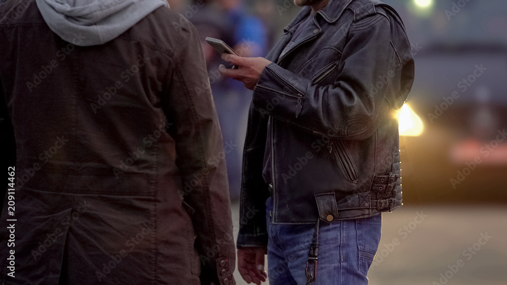 Two men in jackets order taxi outdoor, waiting for cab driver to pick them up Two men in jackets order taxi outdoor, waiting for cab driver to pick them up