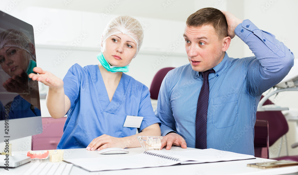 Obraz premium Female dentist explaining diacrisis to shocked man