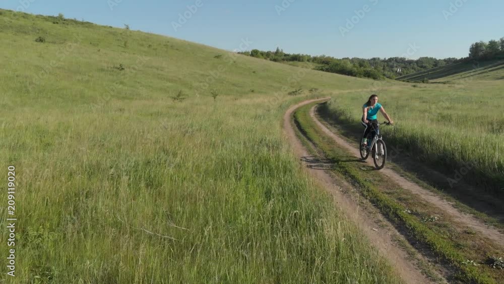 a young girl is driving down the road on a bicycle. a young girl is driving down the road on a bicycle.