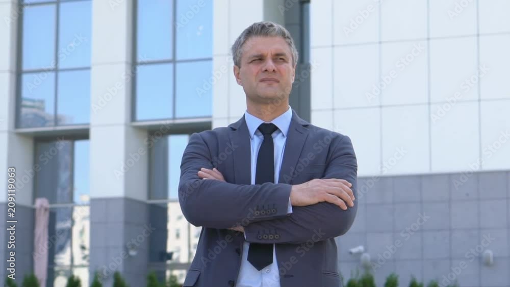 attractive middle-aged man with gray hair. male close-up portrait. serious business man in a jacket on the background of a glass building. Slow motion attractive middle-aged man with gray hair. male close-up portrait. serious business man in a jacket on the background of a glass building. Slow motion