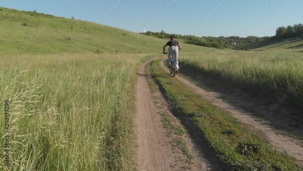 a young guy is riding on the road on a bicycle. a young guy is riding on the road on a bicycle.