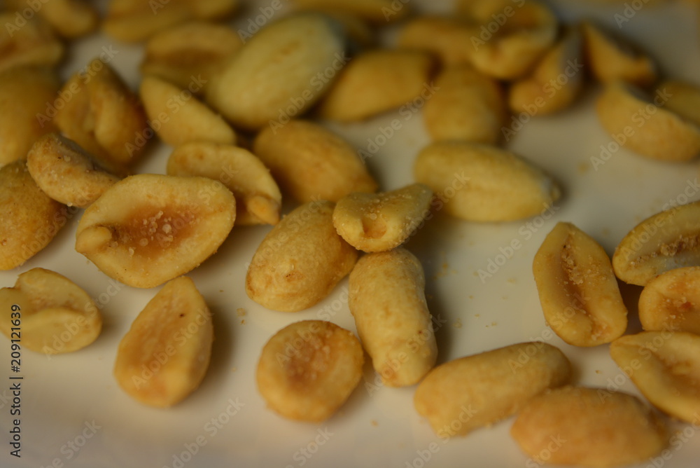 On white glass plate are peanut nuts with salt fried in yellow earth-nut, groundnut, goober, monkeynut On white glass plate are peanut nuts with salt fried in yellow earth-nut, groundnut, goober, monkeynut