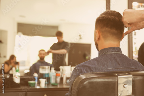 Professional barber working with client in hairdressing salon. Hipster fashion