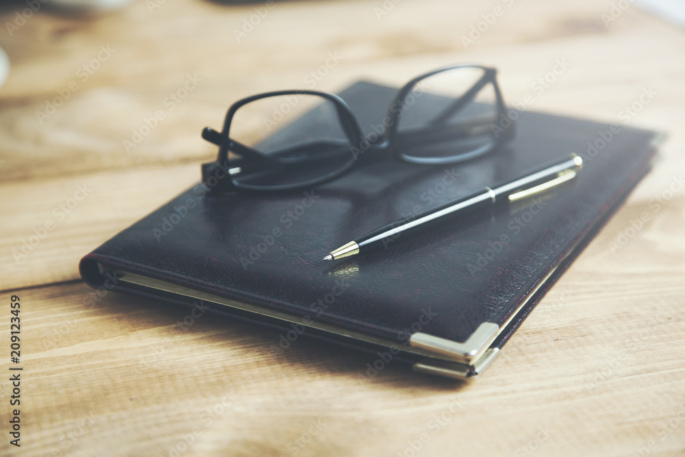 Blank notepad with pen and glasses on office wooden table Blank notepad with pen and glasses on office wooden table