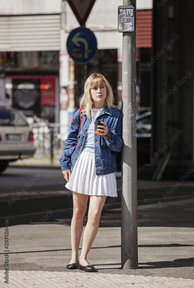 Young woman leaning on a pole waiting to cross the street. Young woman leaning on a pole waiting to cross the street.