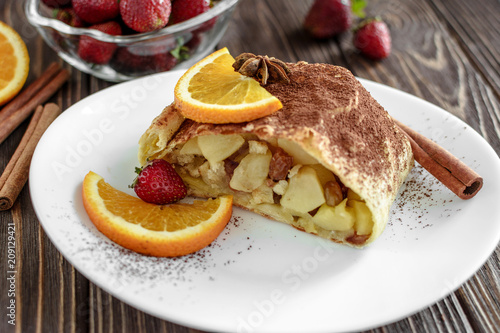 Homemade strudel with apples on a wooden background