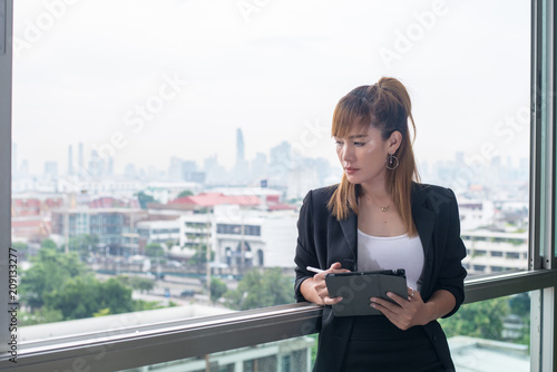 Free Download Young business woman with tablet in the office against panoramic windows - GFXLoad