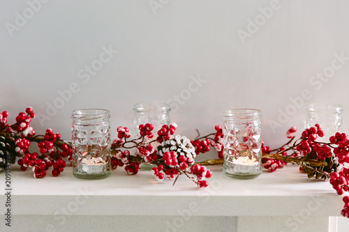 Red berry Christmas garland and votive candles on a mantlepiece. Copy space. photo