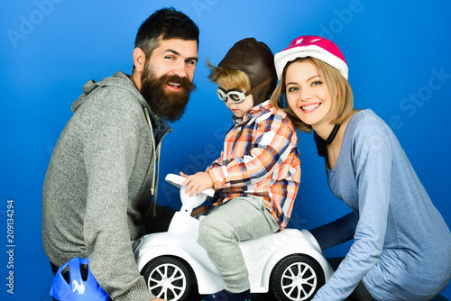 Happy family. Parenthood. Parenting. Little boy with toy car. Parents with son. Parents play with son in toy car. Family in protect sport helmets. Safety people concept.