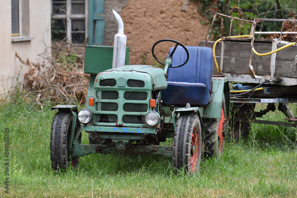 An old and rusty tractor with a trailer nearby the village Bernburg-Germany. An old and rusty tractor with a trailer nearby the village Bernburg-Germany.