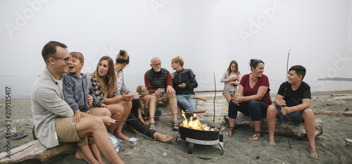 Multi generational family hanging out together around fire on the beach photo