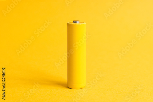 Fotografia Single yellow battery on a yellow pastel background
