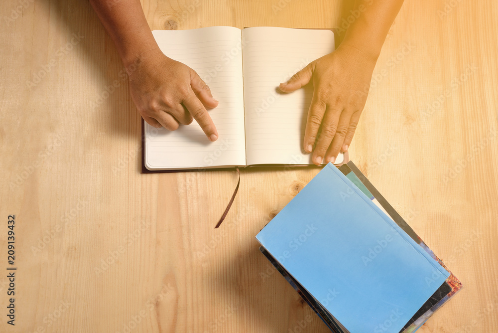 Human hands open blank notebook on the wooden table. Human hands open blank notebook on the wooden table.