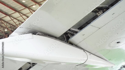 Repair of the aircraft. Repair the flap of the wing of a passenger plane. The pilot checks the wing flap. The plane is in the hangar to repair. The white plane is being repaired in the hangar. 4K
