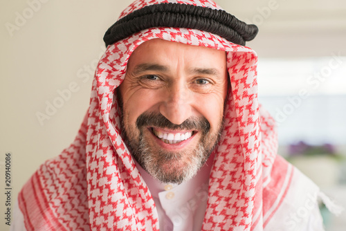Middle age arabian man at home with a happy face standing and smiling with a confident smile showing teeth