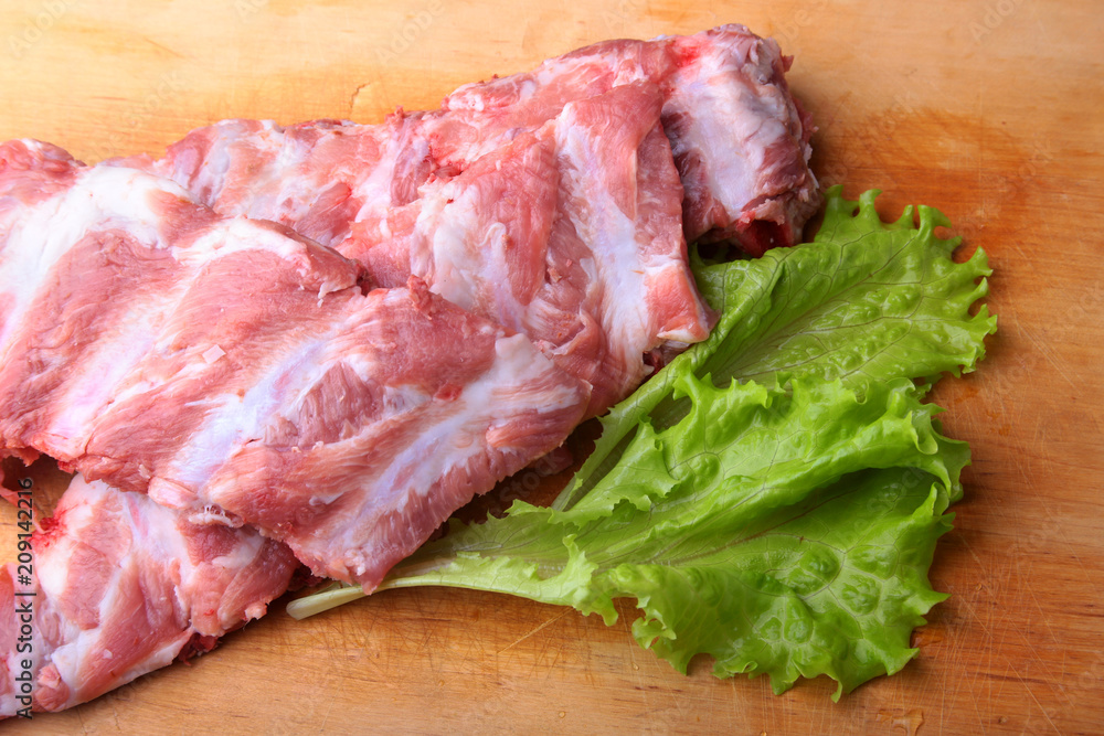 Raw Ribs on a rustic cutting board with salt, pepper and grinder for spices . copy space. Top View. Raw Ribs on a rustic cutting board with salt, pepper and grinder for spices . copy space. Top View.