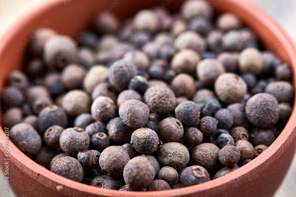 Close-up clay bowl with dried allspice berries on vintage wooden background, top view, macro, shallow depth of field. Close-up clay bowl with dried allspice berries on vintage wooden background, top view, macro, shallow depth of field.