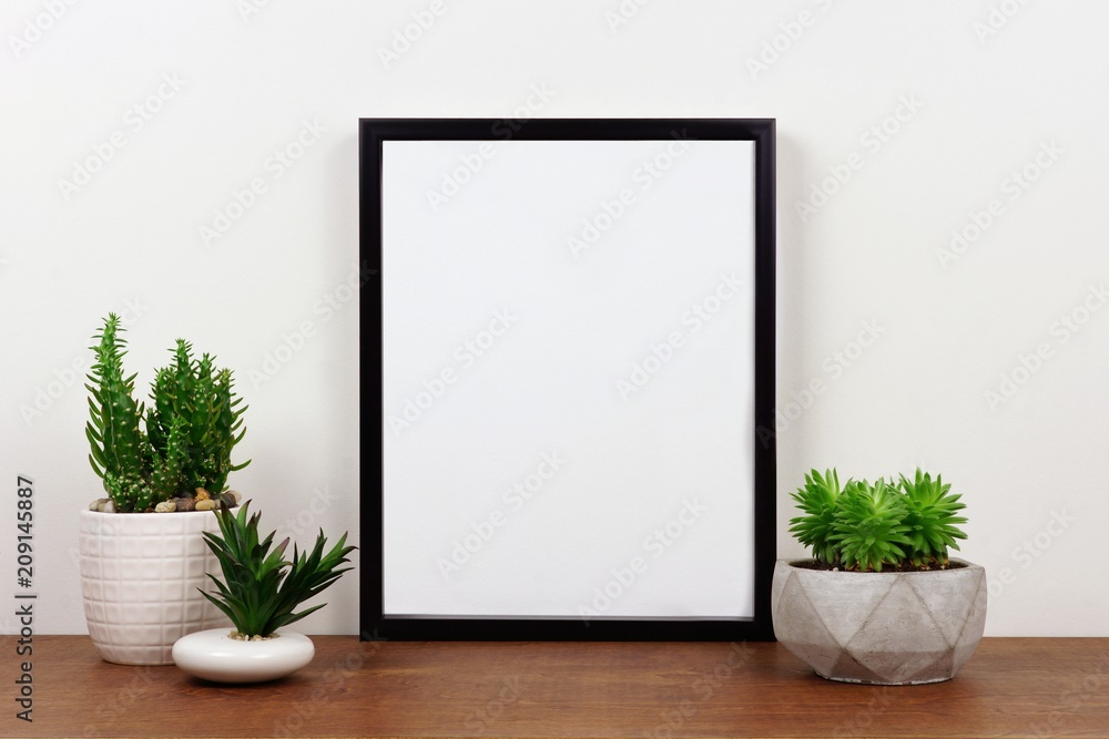 Mock up black frame with succulent plants on a shelf or desk. Wood shelf and white wall. Portrait frame orientation. Mock up black frame with succulent plants on a shelf or desk. Wood shelf and white wall. Portrait frame orientation.