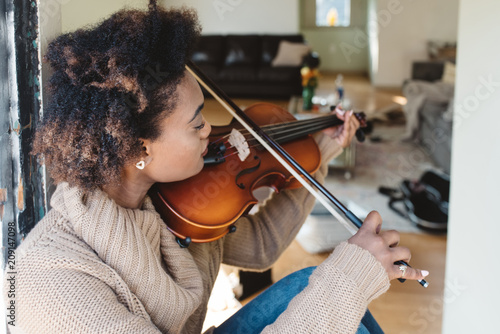 A young woman playing the viola at home