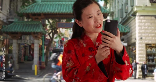 Smiling millennial woman using smartphone to take selfie in front of China Town gate, Young Asian woman wearing traditional Chinese fashion in San Francisco California, 4k
