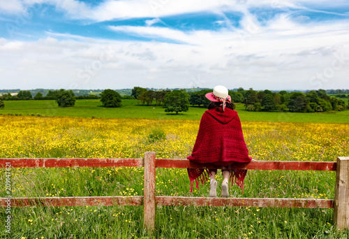 Woman looking into field while sitting on fence