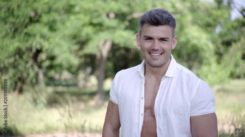 Young handsome model man posing in the city park. European guy with an adorable smile on the background of nature Young handsome model man posing in the city park. European guy with an adorable smile on the background of nature