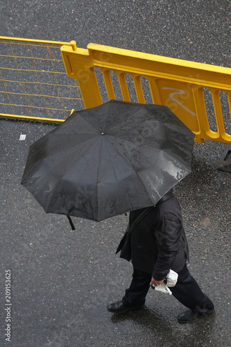 Hombre caminando bajo la lluvia. Paraguas.
