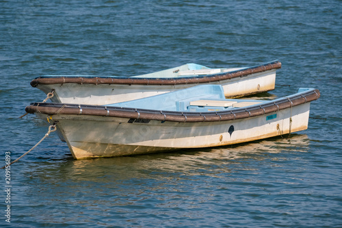 川に浮かぶ二艘の舟、白い木製ボート。