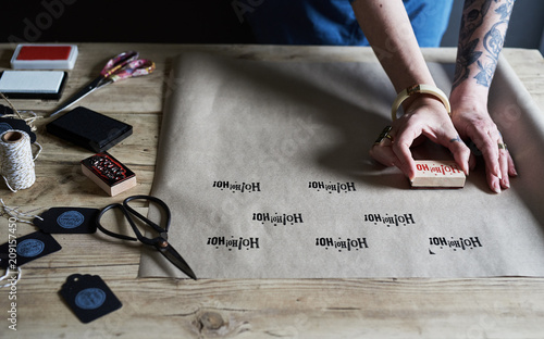 Woman making homemade Christmas gift wrap paper with ink stamp and brown paper. photo
