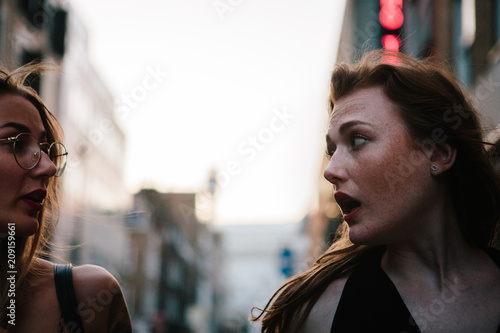 Two attractive millenial women chatting in the street
